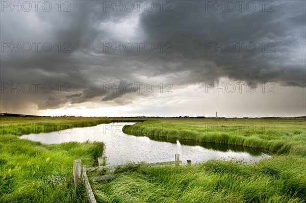 Storm clouds over a pond in coastal grazing marsh habitat