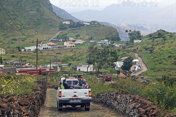 Tourists and locals transported in the back of the pickup truck in the rural landscape on Sao Nicolau Island