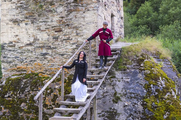 Georgian couple in traditional dress descending the wooden stairs from the Tower of Love