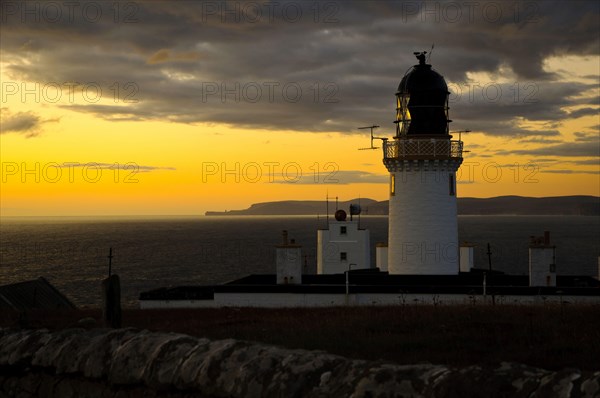 View of clifftop lighthouse at sunset