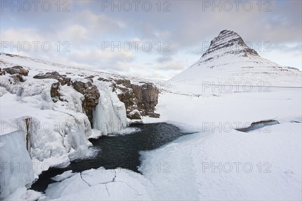 Kirkjufell mountain and the frozen waterfall Kirkjufellsfoss on Snaefellsnes peninsula in the snow in winter