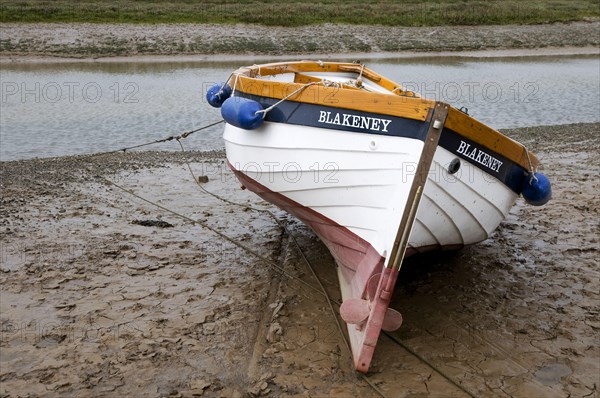 Boat moored on mud at edge of coastal stream