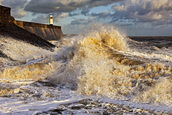 Wave-bombed seafront and coastal town lighthouse