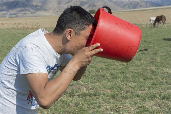 Kazakh man drinking fresh mare's milk from a bucket