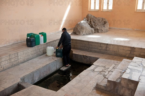 Man scooping water at Moses Spring