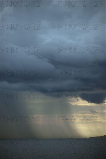 Rainstorm approaching over sea at dusk