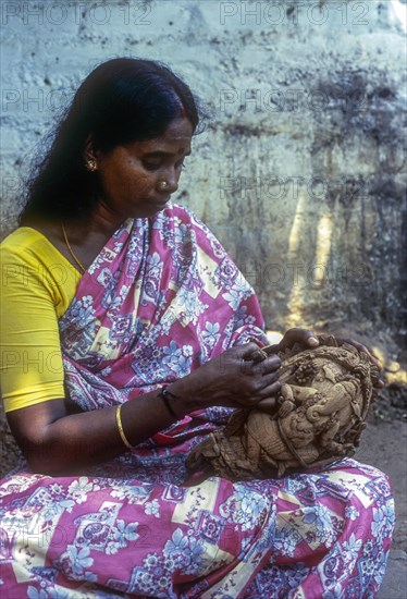 A woman carving on the shell of coconut