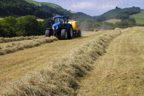 Contractor with New Holland T7040 tractor and New Holland big baler baling hay on organic farm