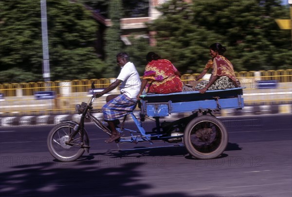 People journeying on a tricycle on the beach road in Chennai