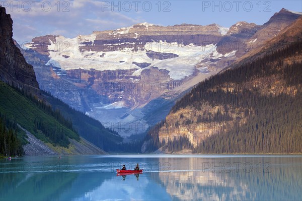 Tourists in a red canoe on glacial Lake Louise with Victoria Glacier
