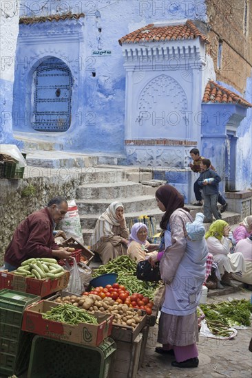 People at the market next to blue houses in the city