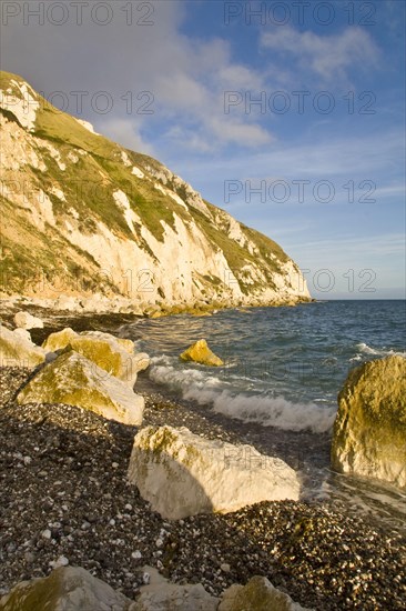 Coastal headland with small waves breaking on shingle and rocky beach