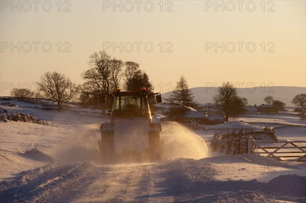 Snow plough clearing snow-covered country road