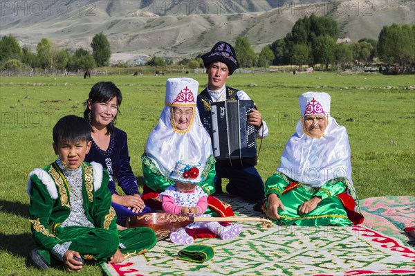 Kazakh family in traditional dress listening to the music of an accordion player