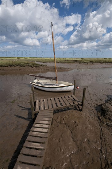 Yacht moored in coastal creek at low tide