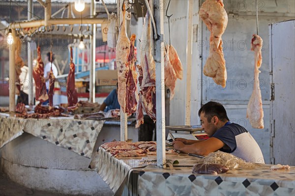 Kyrgyz vendor sells meat at an unhygienic butcher's stall at a food market in the city of Osh on the Silk Road in Kyrgyzstan