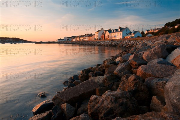 View of the sea wall and houses of a coastal village overlooking the harbour at sunset