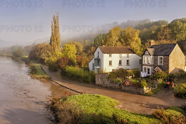 View of a riverside village in the mist at dawn