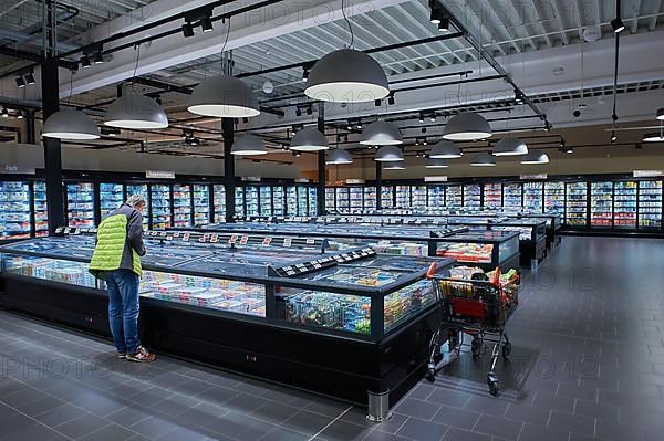 A man stands at a refrigerated display case