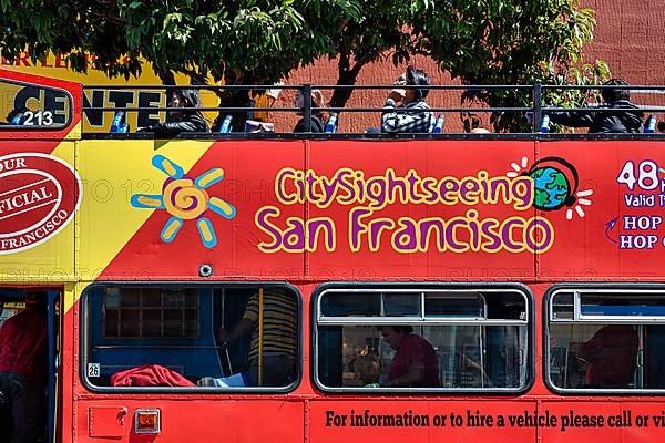 Red double-decker bus with passengers and advertising for sightseeing