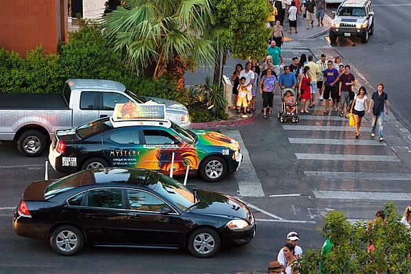 Car and taxi with colourful advertising at a busy intersection