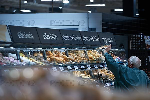 Man in front of bakery self-service lifts a flap