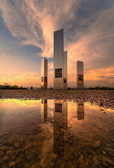Historical memorial with reflection in puddle at sunset