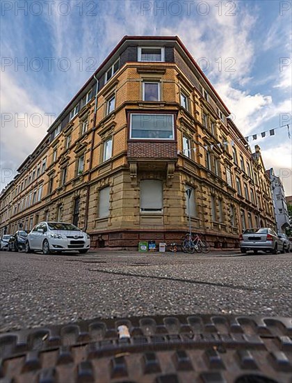 View of historic corner building in the city centre with manhole cover lid in the foreground