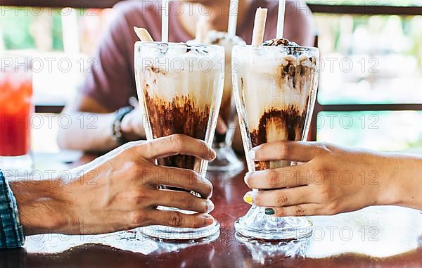 Man and woman hand toasting and holding two milkshake. Two hands toasting with milkshake in a cafe