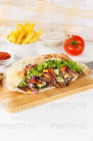 Doener Kebab Doner Kebap half fast food meal in pita bread with fries on wooden board in Stuttgart