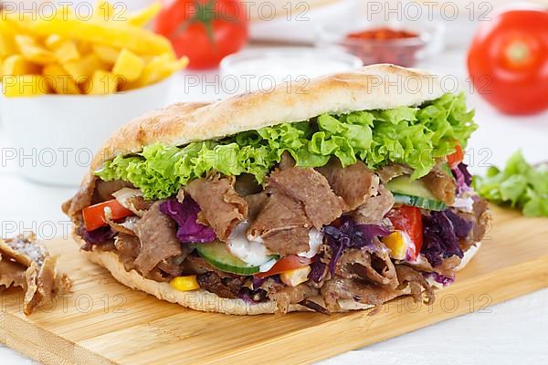 Doener Kebab Doner Kebap fast food meal in pita bread menu with fries on wooden board in Stuttgart