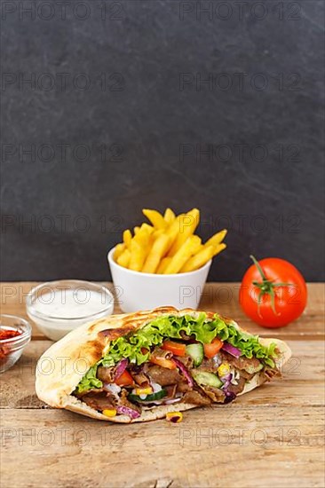 Doener Kebab Doner Kebap fast food meal in pita bread menu with fries on wooden board in Stuttgart