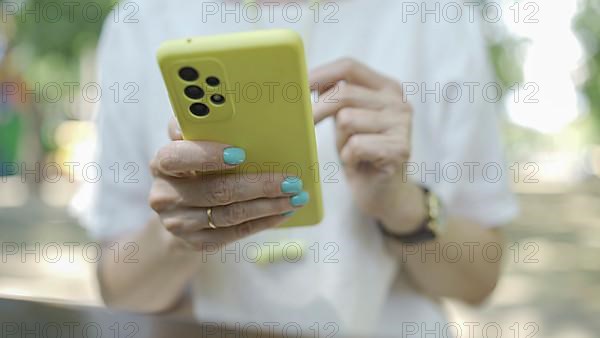 Close up of mature woman's hands use smartphone. Soft focus