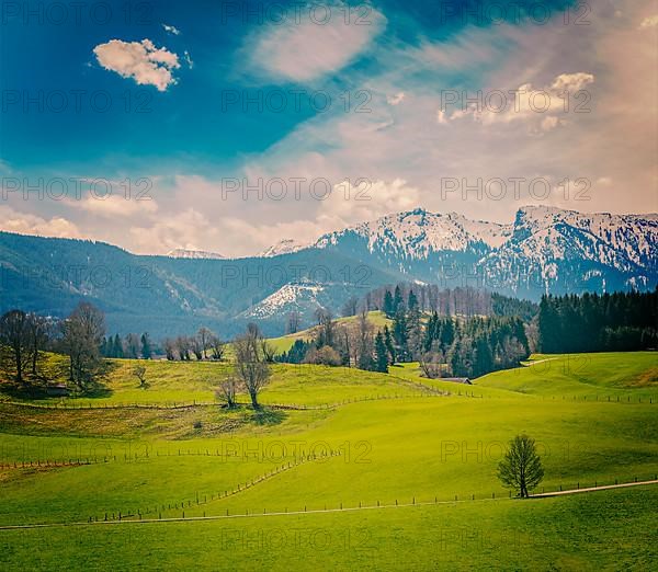 Vintage retro hipster style travel image of German idyllic pastoral countryside in spring with Alps in background. Bavaria