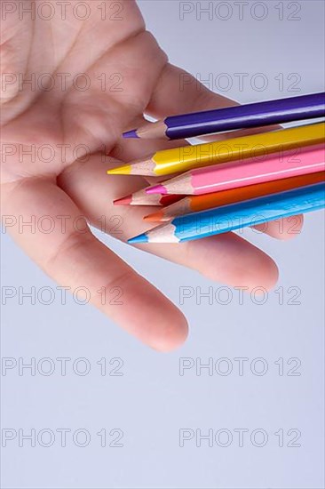 Hand holding color Pencils placed on a white background