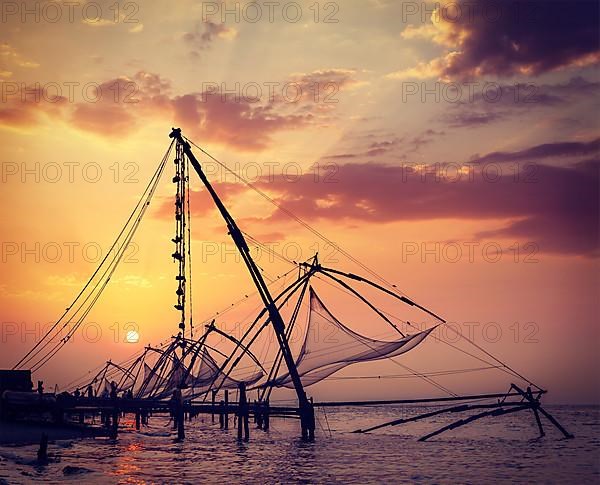 Vintage retro hipster style travel image of Kochi chinese fishnets on sunset. Fort Kochin