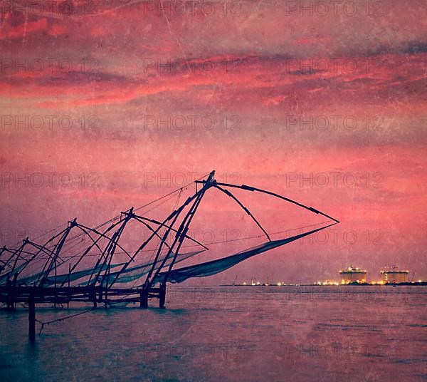 Vintage retro hipster style travel image of Kochi chinese fishnets on sunset. Fort Kochin