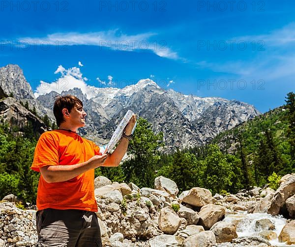 Hiker trekker studying map route on trek in Himalayas mountains. Himachal Pradesh