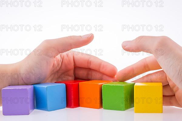 Hand playing with colorful cubes on a white background