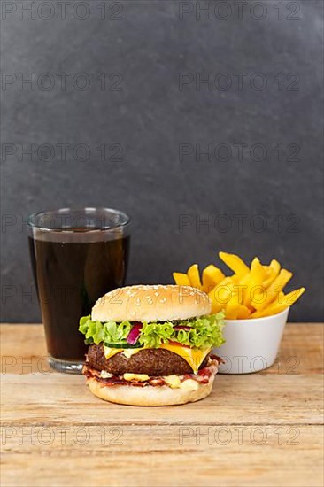 Hamburger cheeseburger fast food meal menu with fries and coke drink on wooden board in Stuttgart