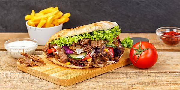 Doener Kebab Doner Kebap fast food meal in pita bread menu with fries on wooden board Panorama in Stuttgart