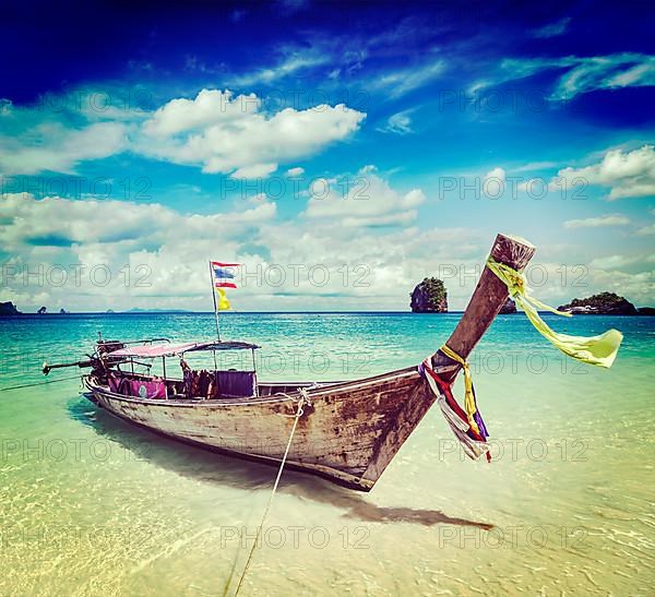 Vintage retro effect filtered hipster style travel image of long tail boat on tropical beach