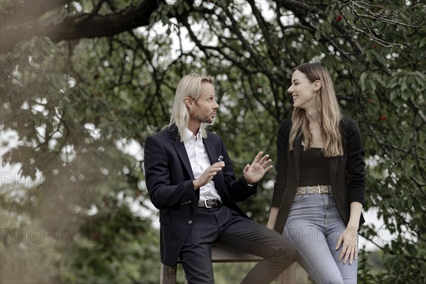 Man and woman talking on a wooden table in nature