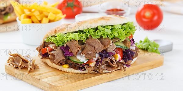 Doener Kebab Doner Kebap fast food meal in pita bread menu with fries on kitchen board Panorama in Stuttgart