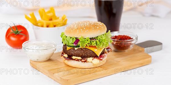 Hamburger cheeseburger fast food meal menu with fries and coke drink on wooden board Panorama in Stuttgart