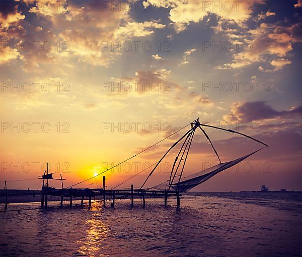 Vintage retro hipster style travel image of Kochi chinese fishnets on sunset. Fort Kochin