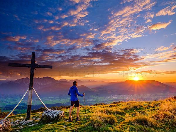 Mountaineers at the Schlenken summit cross at sunset clouds