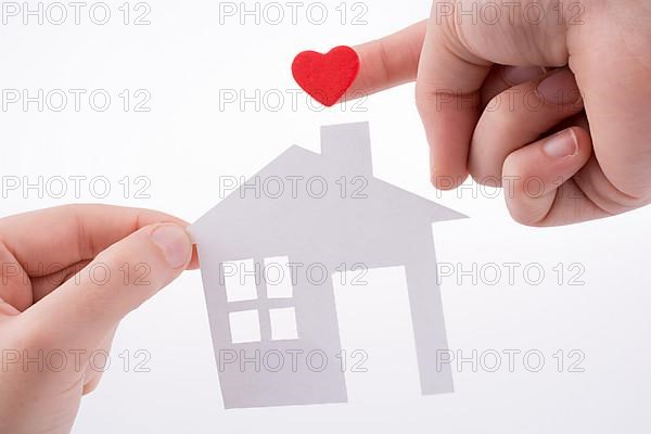 Paper house and heart shape in hand on a white background