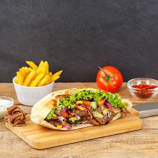 Doener Kebab Doner Kebap half fast food meal in pita bread with fries on wooden board square in Stuttgart