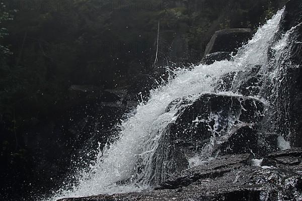 Acascade that stands out against the black background of a cliff